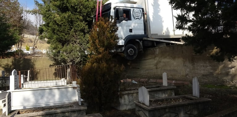 Karabük’te sürücüsünün navigasyon uygulamasına uyarak girdiği yolda kontrolden çıkan kamyon askıda kalarak mezarların üzerine düşmekten son anda kurtuldu.